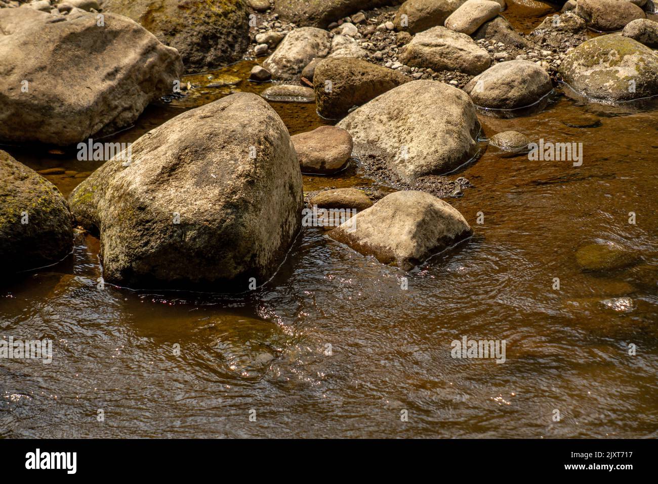 Water Flow From Rocks Expanse of volcanic rocks in a small river with a calm water flow, the ...