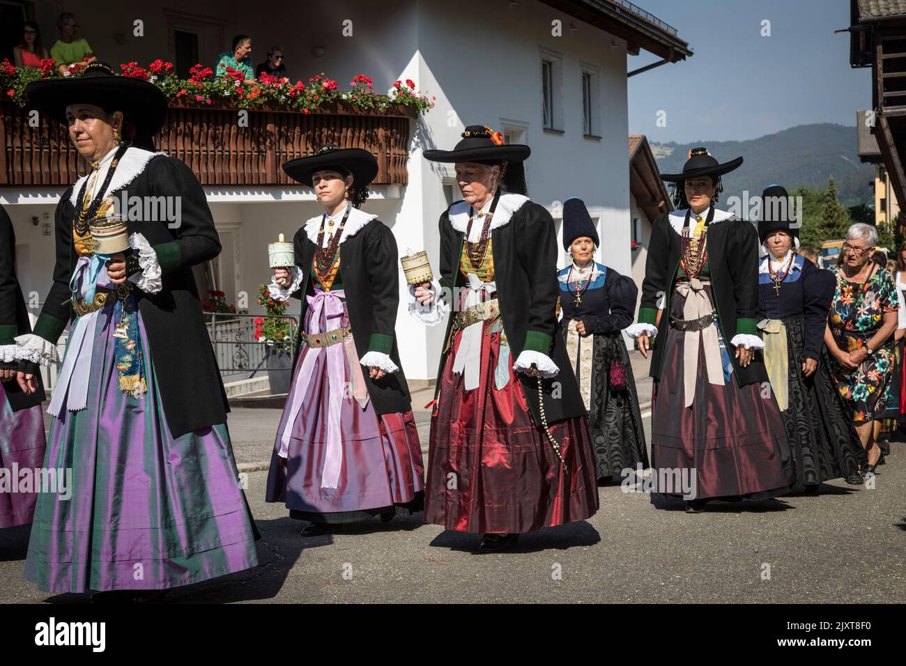 Women wearing traditional local period costume of wide brimmed hats and long colourful skirts, take part in a 'Corpus Christi' church procession in Or Stock Photo
