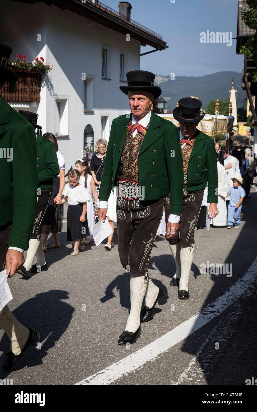 Men wearing traditional local period costume of leather breeches and low top hats take part in a 'Corpus Christi' church procession in Ortisei, Italy. Stock Photo