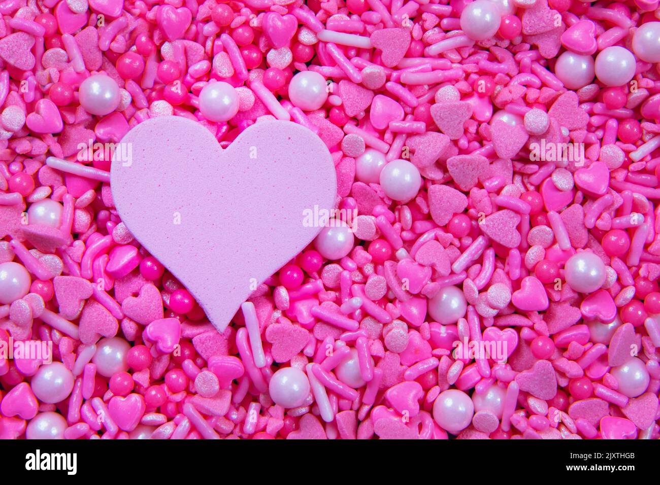 Full frame pink heart sprinkles and a pink heart shape, copy space Stock Photo