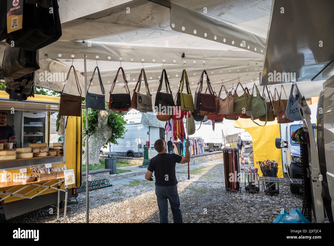 Market trader hangs up leather bags ready for sale on his stall, Italy Stock Photo