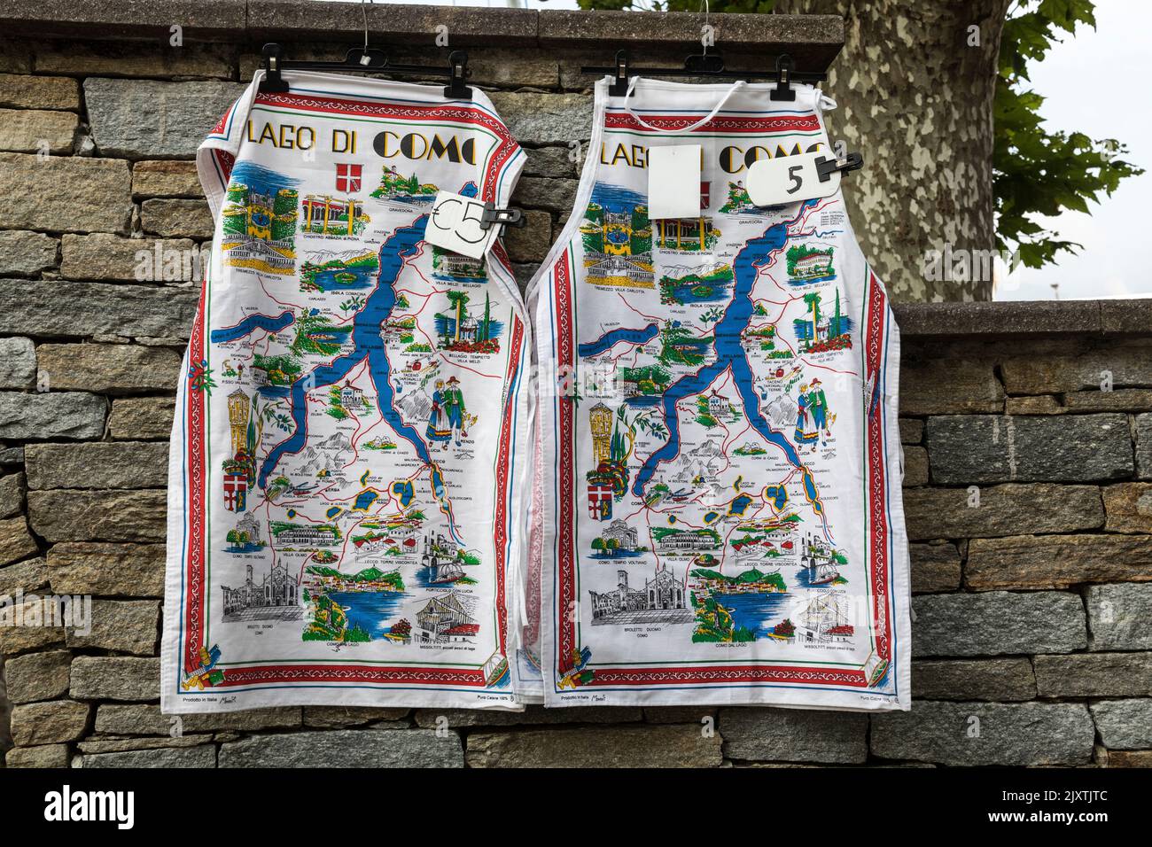 Tea towels for sale depicting Lake Como (Lago di Como) hang from a stone wall, Italy. Stock Photo