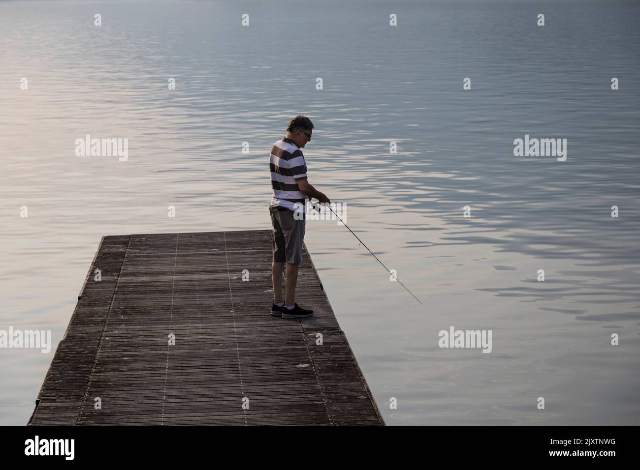 Man fishing on a lake from a pontoon. Stock Photo