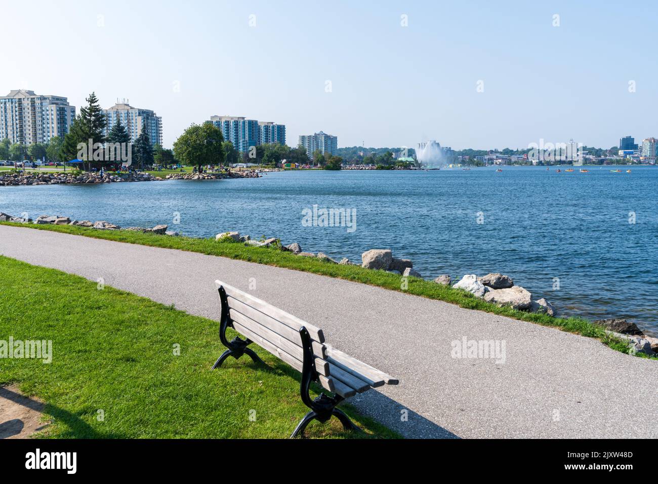 Centennial Park walking Path and wooden bench. Downtown Barrie curves around the shore of Kempenfelt Bay, Lake Simcoe in summer time. Ontario, Canada. Stock Photo