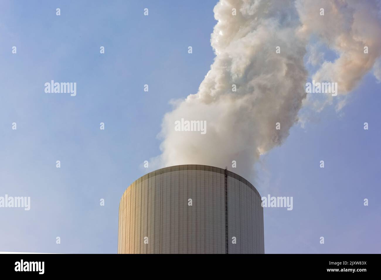 Qualmender Schornstein eines Kohlekraftwerks vor blauem himmel Stock Photo