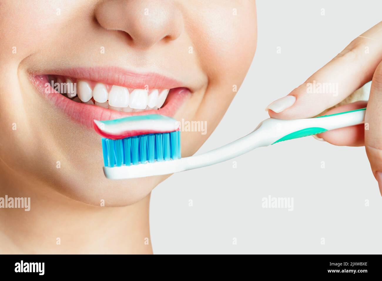 Young beautiful woman is engaged in cleaning teeth. Beautiful smile healthy white teeth. A girl holds a toothbrush. The concept of oral hygiene Stock Photo
