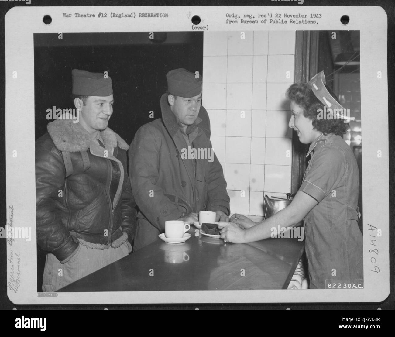 The British Naafi (Navy, Army, Air Force Institute) Which Maintained Canteens On The Bleak, Wind-Swept Bomber Stations Until The American Red Cross Was Able To Take Over, Did A Magnificent Job. Here, Dorine Oakley (Naafi) Serves Tea To Pvt. Hy Phillips, Stock Photo