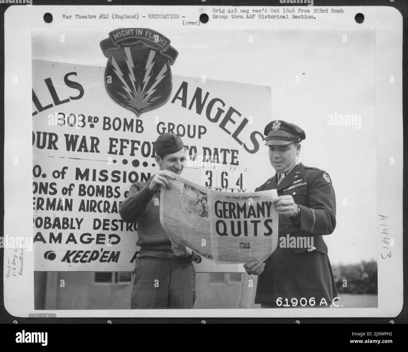 Germany Quits - Tall Black Headlines In The 'Stars And Stripes' Announced The End Of Hostilities In Europe To Two Crew Members Of The 303Rd Bomb Group. In The Background Is A Chart Showing The Operational Record Of The 'Hell'S Angels'. England. 8 May 1 Stock Photo