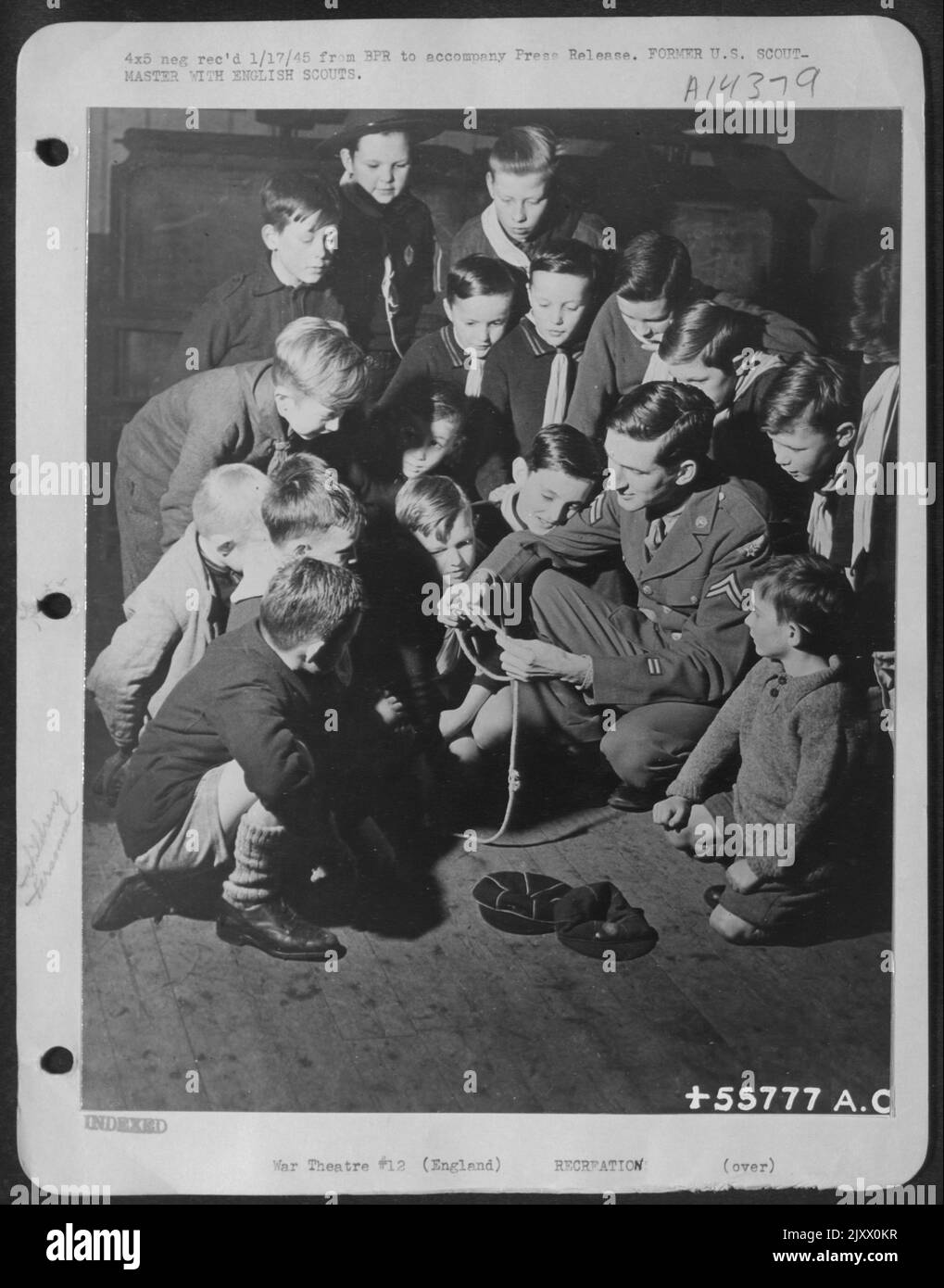 Kids are kids, wherever they may be--and no one knows it better than Cpl. Glen D. Hunt, ofrmer Seattle assistant Scoutmaster who teaches an English Cub pact the mysteries of knot-tying. Hunt, a Chemical Warfare expert with the Air Service Command Stock Photo