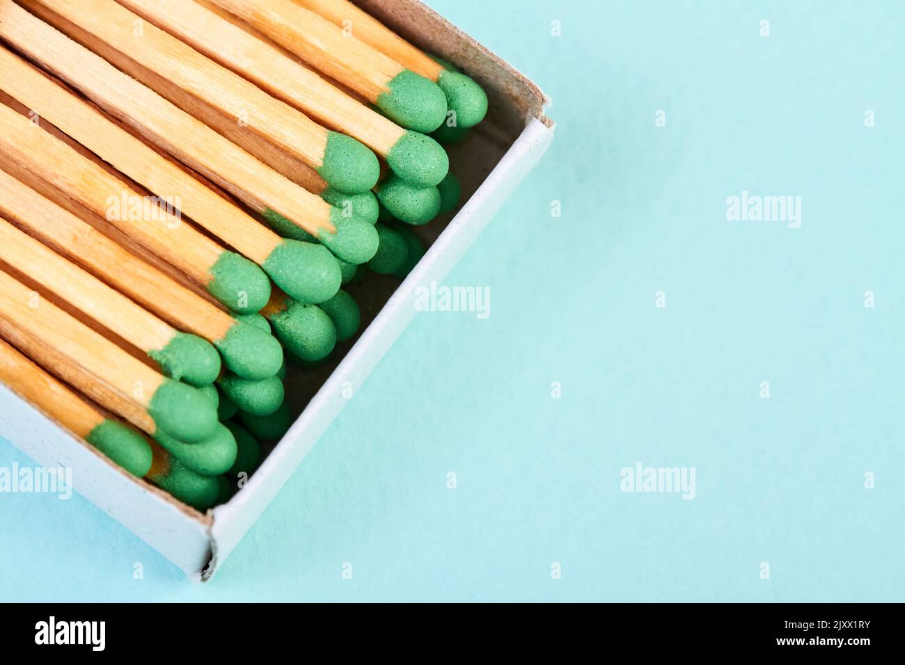 Many matches with green heads in a matchbox on a blue background with