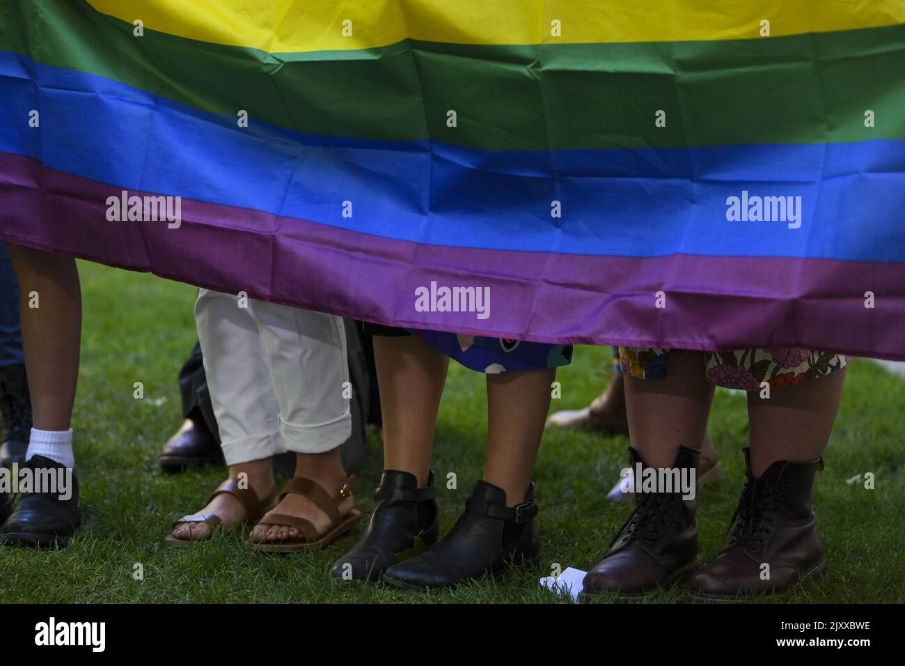 Members of the LGBTQ Youth stand behind a rainbow flag during a press