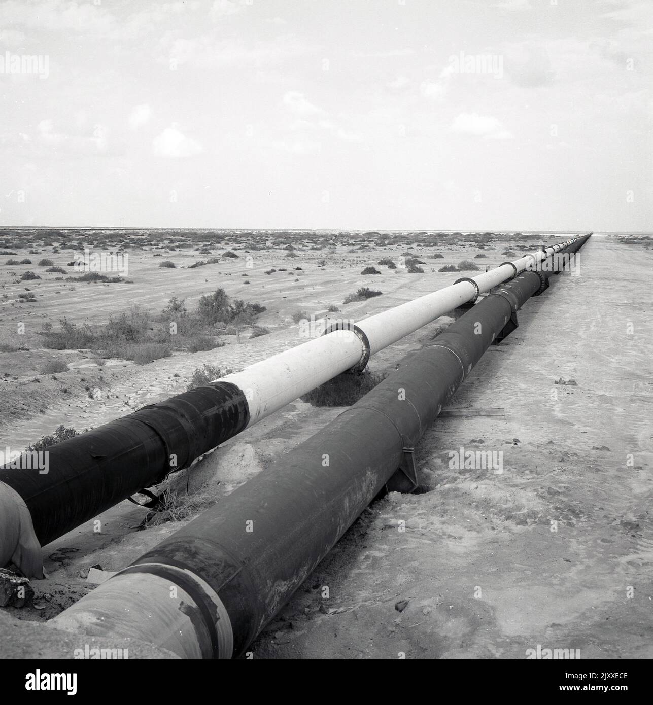1960s, historical picture showing two crude oil pipelines beside each other, extending across a large barren desert area, Saudi Arabia. Stock Photo