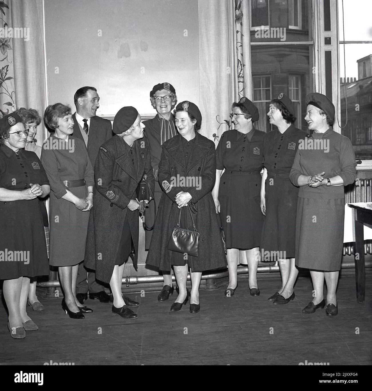 1965, historical, ladies of the WVS, the Women's Voluntary Services, gathered together in a room for a photo at Fife, Scotland, UK, several in their uniform, with emblems on their shirts, saying W.V. S Civil Defence. Now known as The Royal Voluntary Service, it was the Women's Voluntary Services (WVS) from 1938 to 1966 and then the Women's Royal Voluntary Service (WRVS) to 2004, WRVS to 2013. It was founded in 1938, as a British women's organisation to recruit women into the Air Raid Precautions (ARP). The RVS is a voluntary organisation concerned with helping people in need throughout the UK. Stock Photo