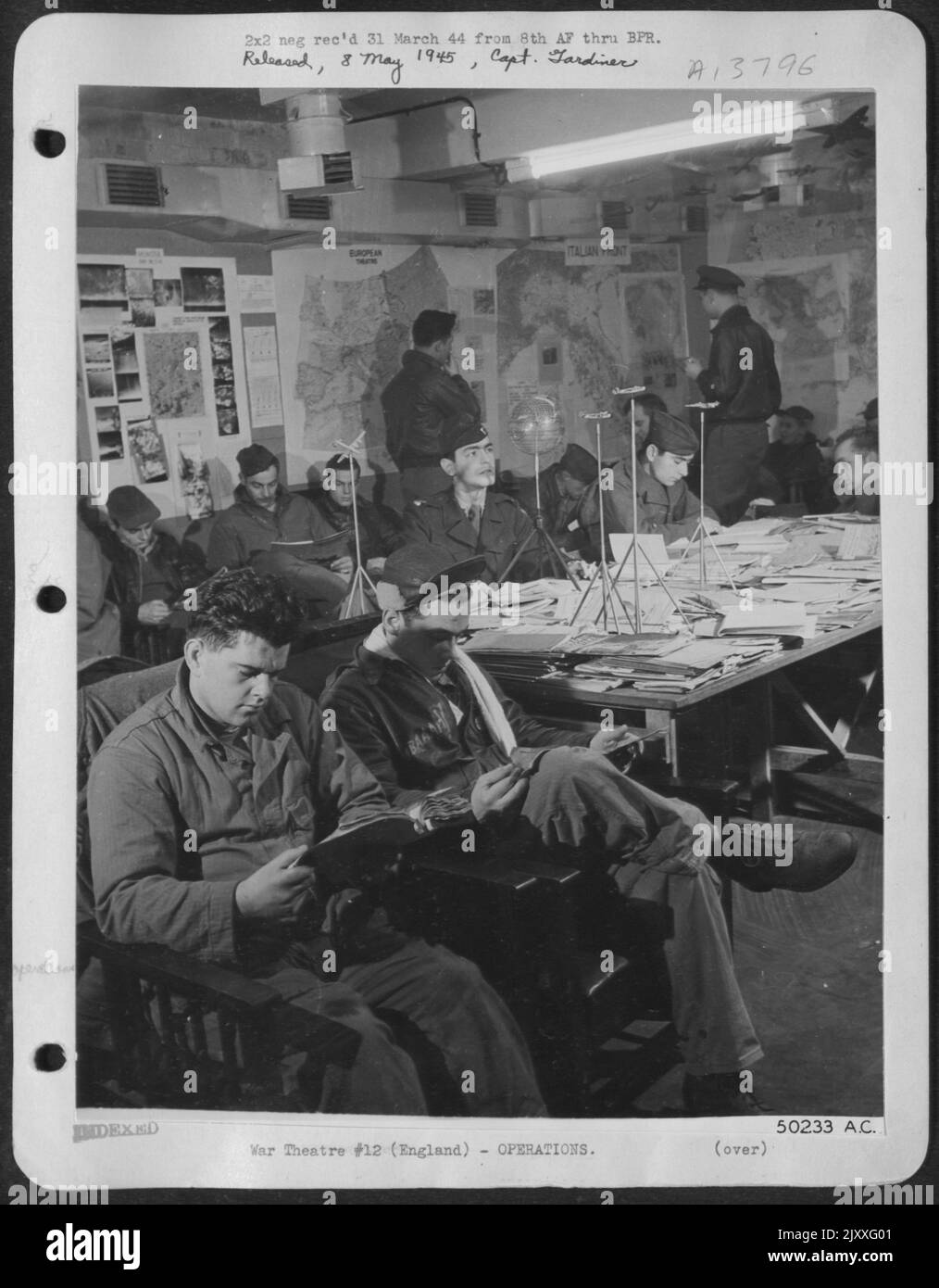 Combat crew men of Liberator spend their spare hours in base intelligence library studing S-2 reports, operational pictures, models of enemy aircraft, and battle maps of all theaters, etc., in order that they may keep constantly abreast of Stock Photo