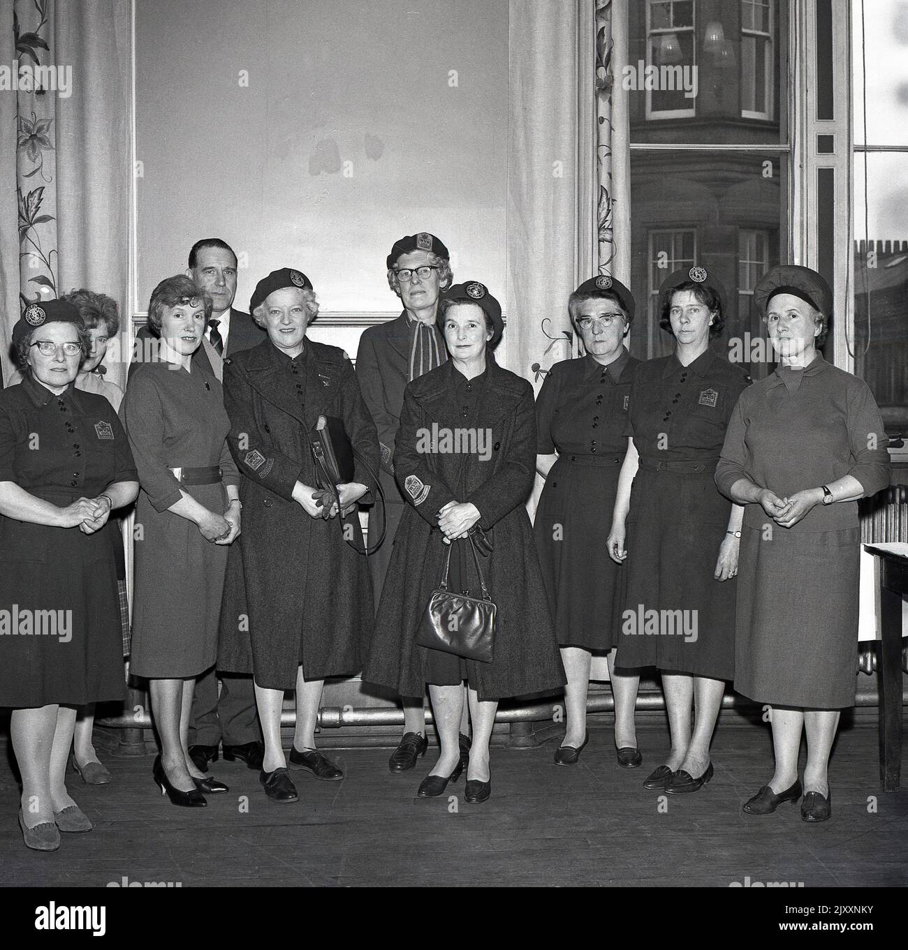1965, historical, ladies of the WVS, the Women's Voluntary Services, gathered together in a room for a photo at Fife, Scotland, UK, several in their uniform, with emblems on their shirts, saying W.V. S Civil Defence. Now known as The Royal Voluntary Service, it was the Women's Voluntary Services (WVS) from 1938 to 1966 and then the Women's Royal Voluntary Service (WRVS) to 2004, WRVS to 2013. It was founded in 1938, as a British women's organisation to recruit women into the Air Raid Precautions (ARP). The RVS is a voluntary organisation concerned with helping people in need throughout the UK. Stock Photo