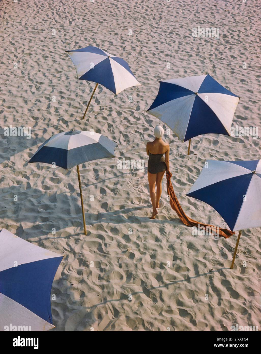 Rear View Portrait of Woman in One-Piece Swimsuit surrounded by Umbrellas on Beach, Toni Frissell Collection, December 1948 Stock Photo