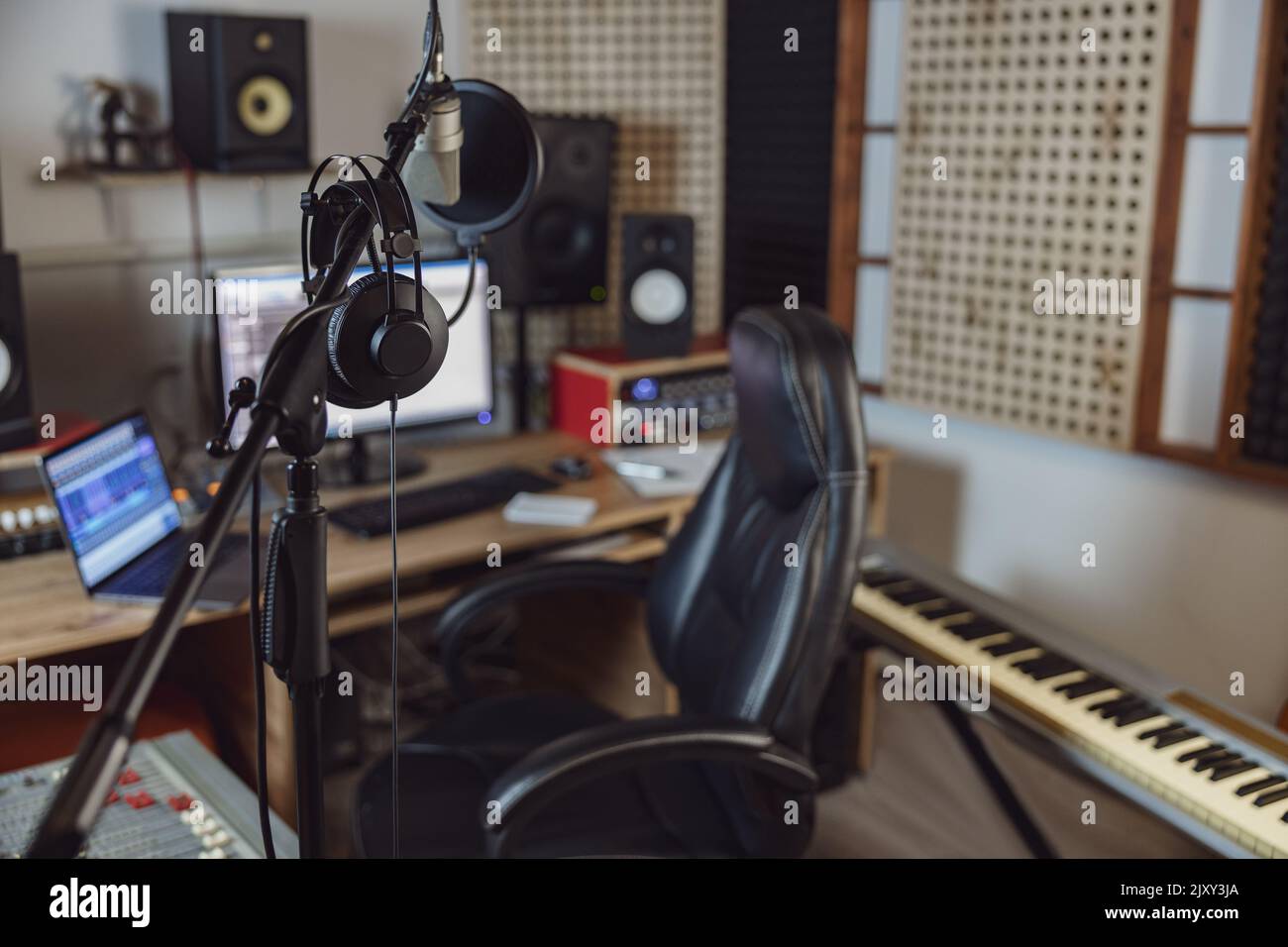 Microphone and headphones in blurred sound engineer office for