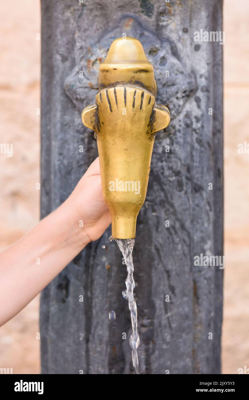 Fresh clean drinking water flows from an outdoor tap as a child turns on the tap Stock Photo
