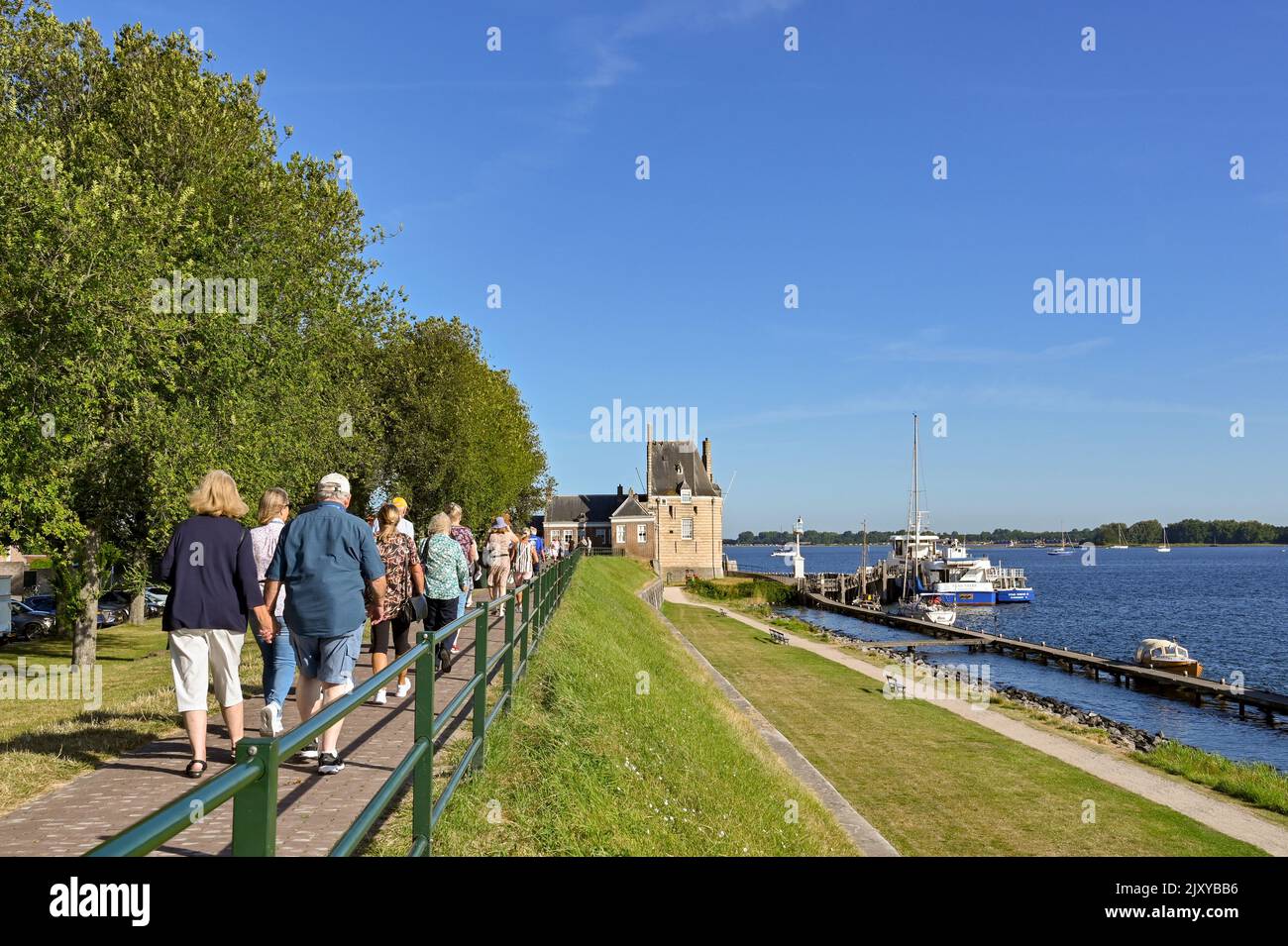 Veere, Netherlands - August 2022: Group of people walking along a footpath to visit the town Stock Photo