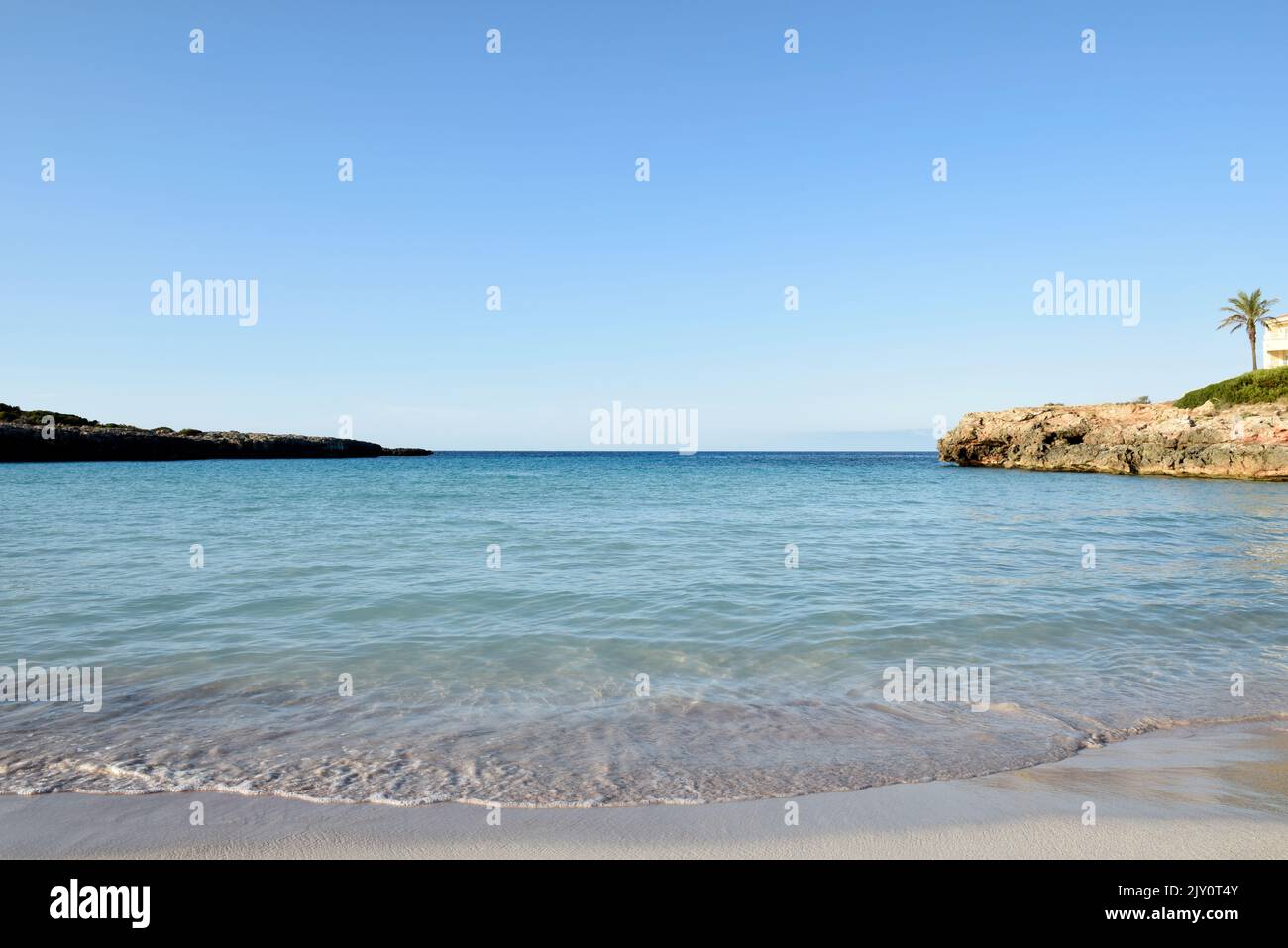 Sea shore at a tropical beach with clear ocean water and sand Stock Photo