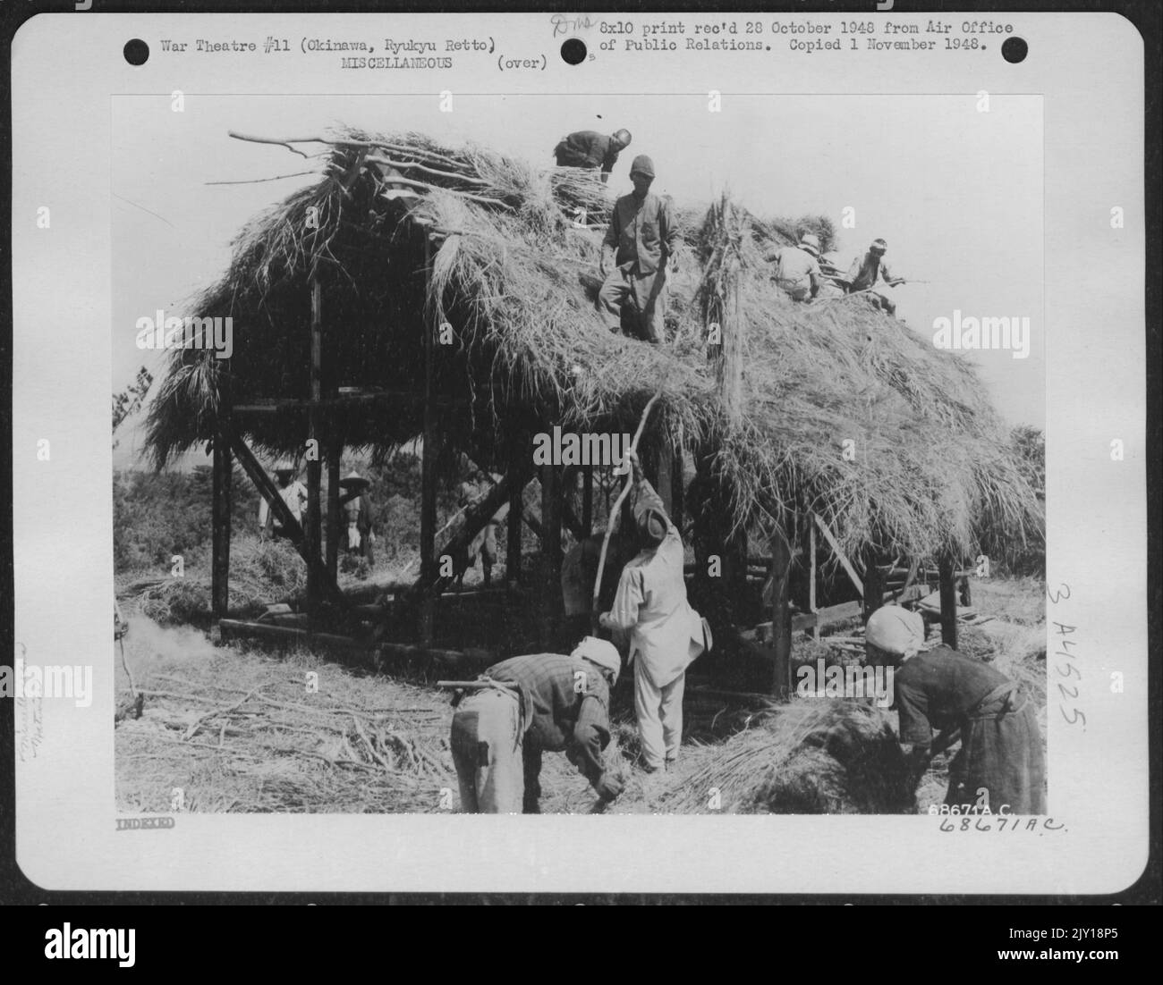 This Will Soon Be Home For A Native Family - Military Government Furnishes The Frames For Native Huts, But The Okinawans Do The Rest. Here A Group Is Busy Putting On The Thatched Roof. Okinawa, Ryukyu Retto. Stock Photo