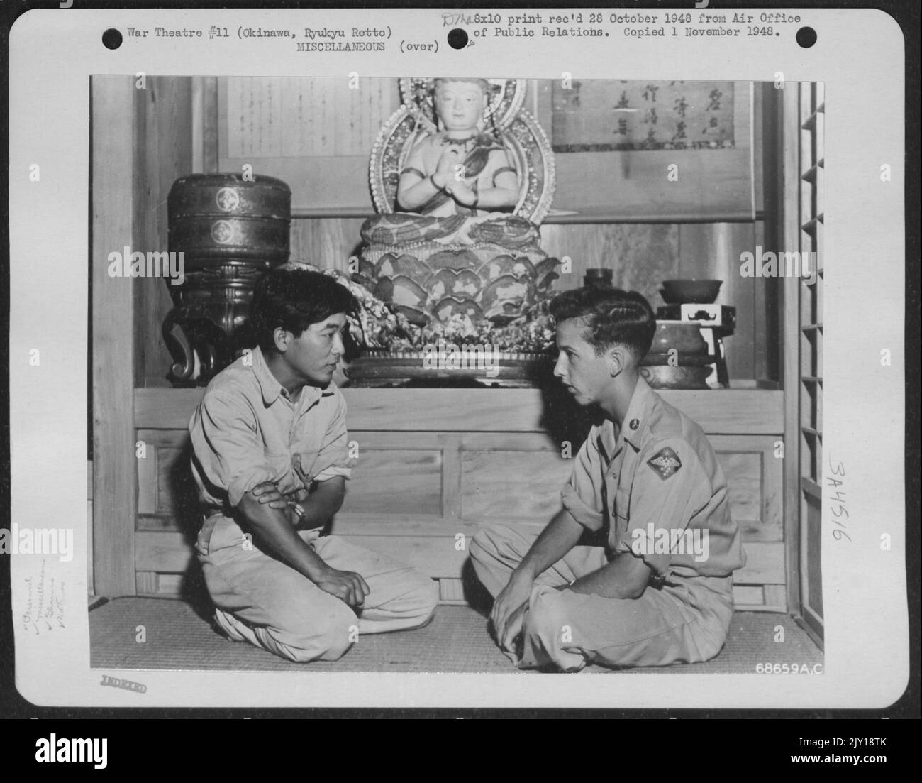 Airman Hears Story Of Goddess Of Mercy - Sergeant Phil C. Geraci, Of Frederck, Maryland, A Photographer Assigned To The 1St Air Division, Sits In Front Of A Buddhist Temple In The Ishikawa Exhibit House And Listens While An Okinawan Guide Explains That Th Stock Photo