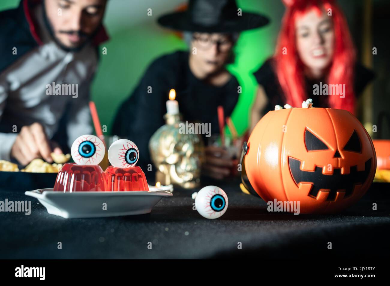 Group of friends in a night halloween party. Devil, witch and dracula eating and drinking Stock Photo