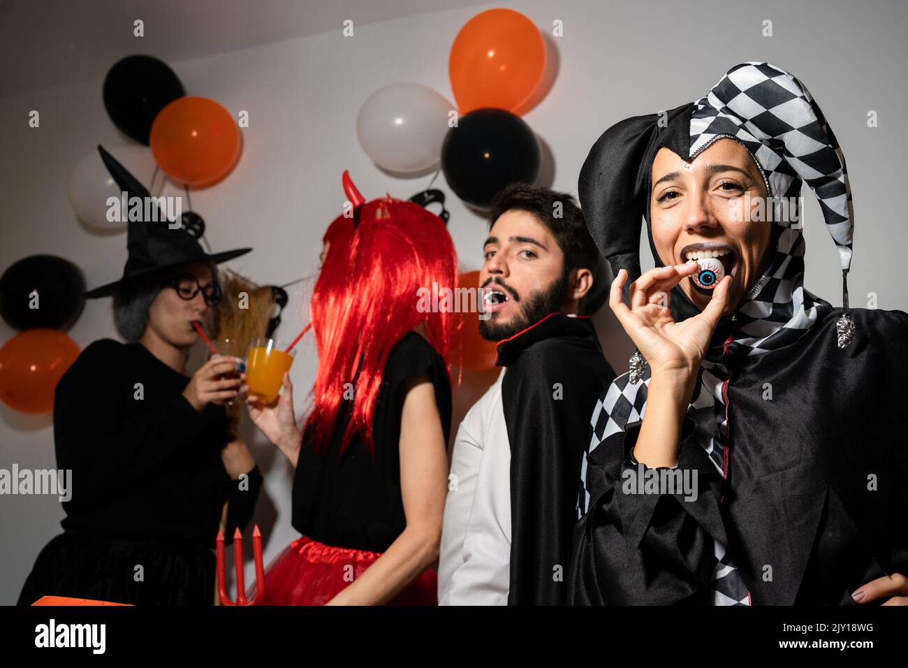 Halloween party at home. Devil, witch, dracula and harlequin posing and having fun Stock Photo
