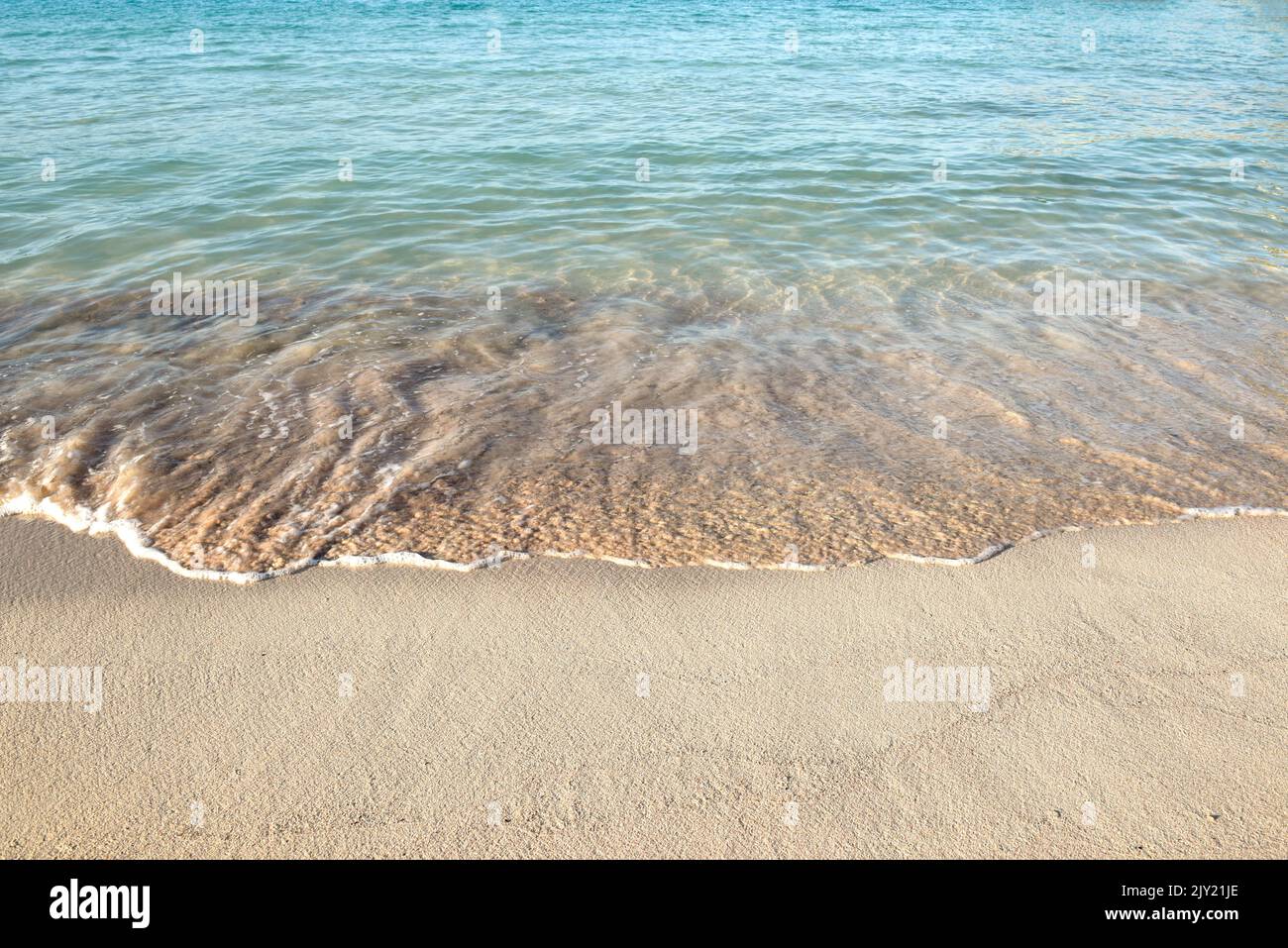 Ocean waves at the shore of a white sand beach Stock Photo