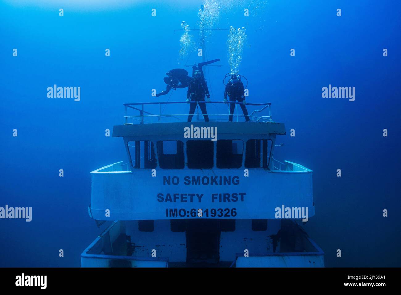 Front view of the bridge of the new white wreck Hephaestus one week after it was scuttled with divers standing on it near Xatt L-Ahmar, Gozo, Malta. Stock Photo