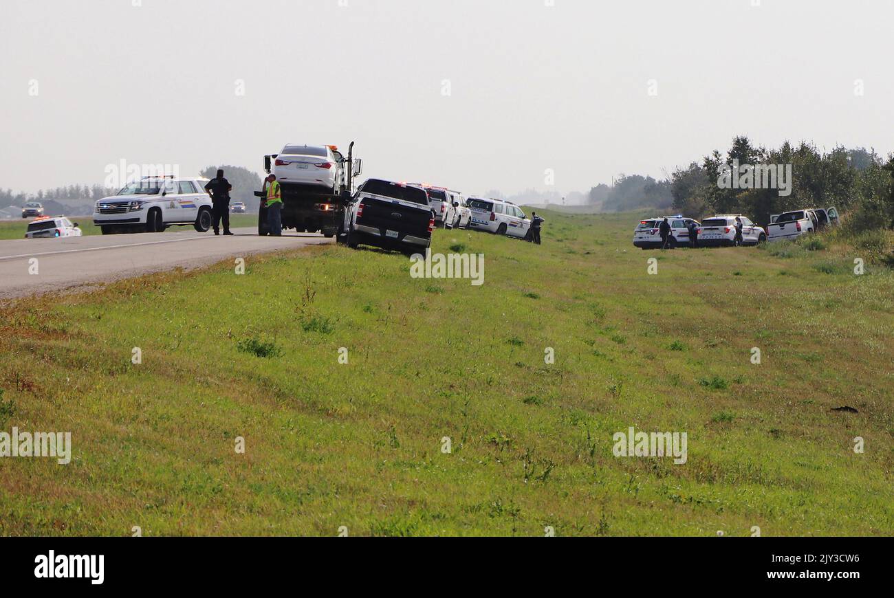 Police and investigators are seen at the side of the road outside