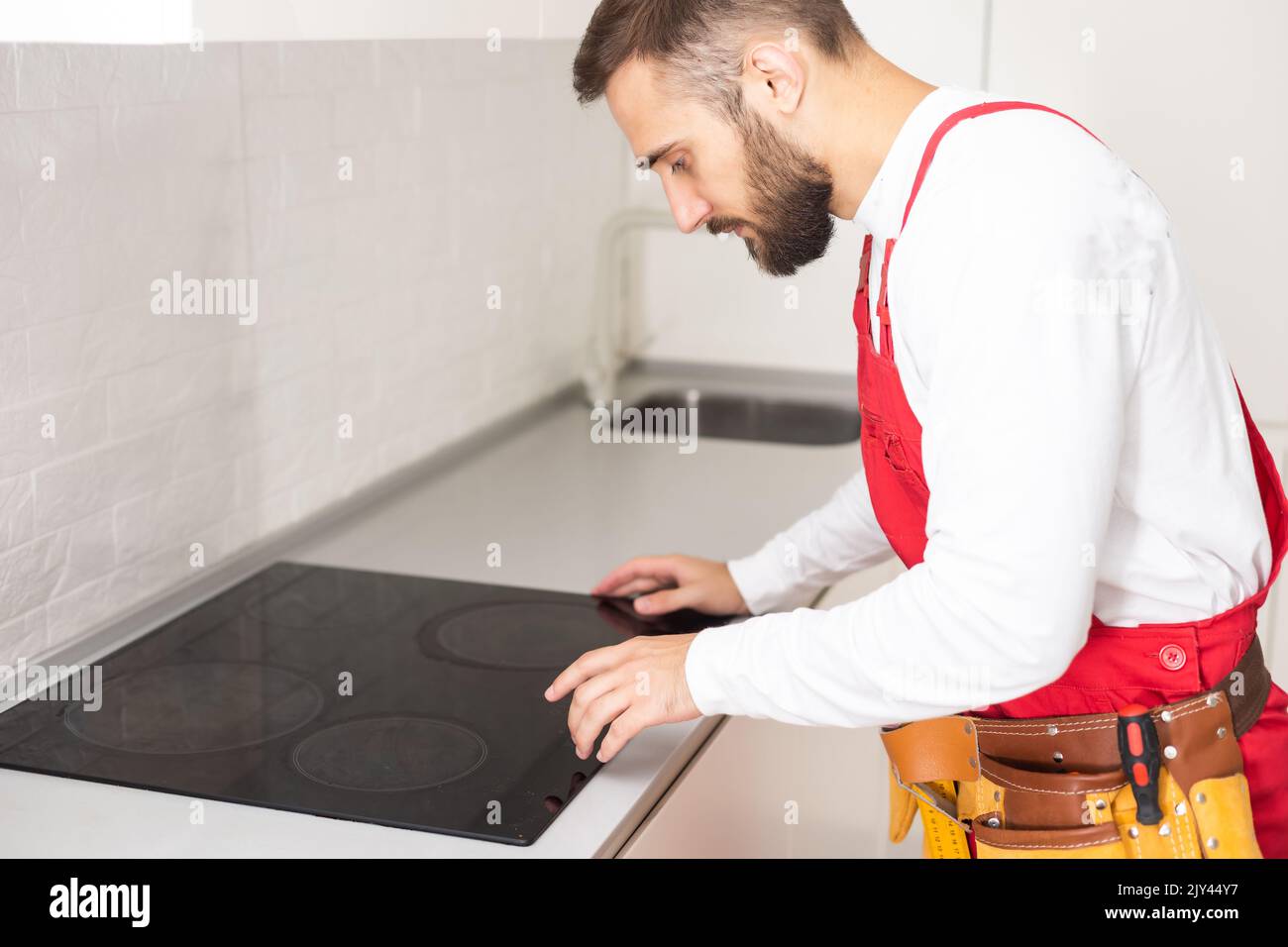 Man electrical repairs kitchen surface apartment. Installing hob in