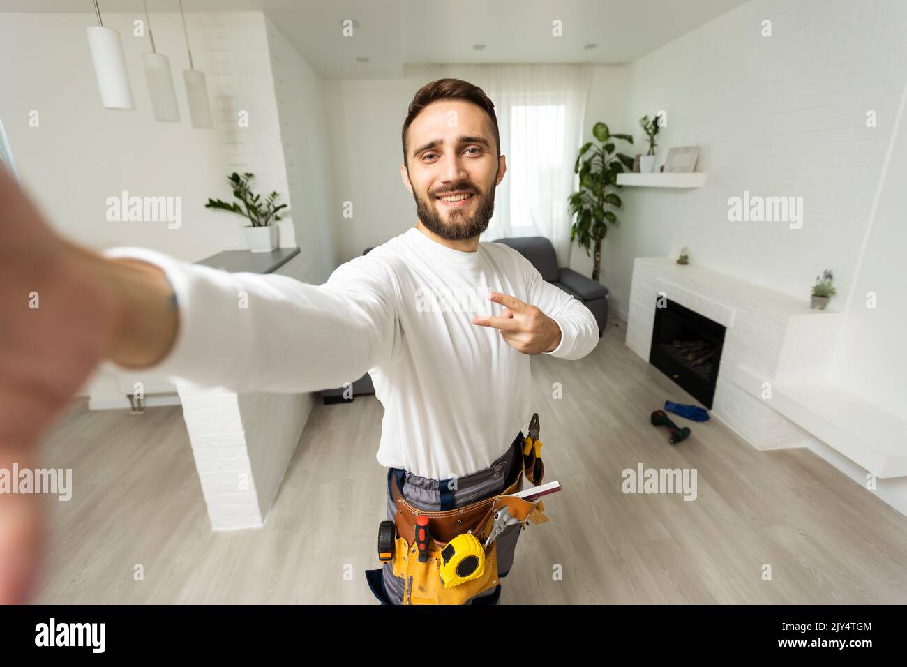 Smiling handsome young builder making selfie with mobile phone Stock Photo
