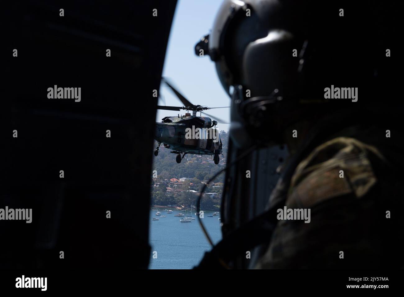 An Australian Army loadmaster looks out from an Army Black Hawk ...