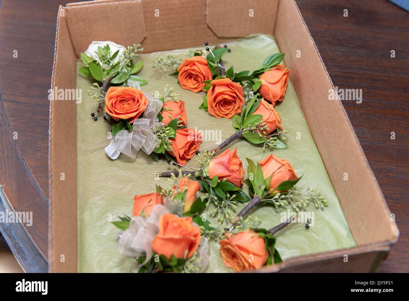 Box of orange rose boutonnieres are ready to be pinned on each member of wedding party. Stock Photo