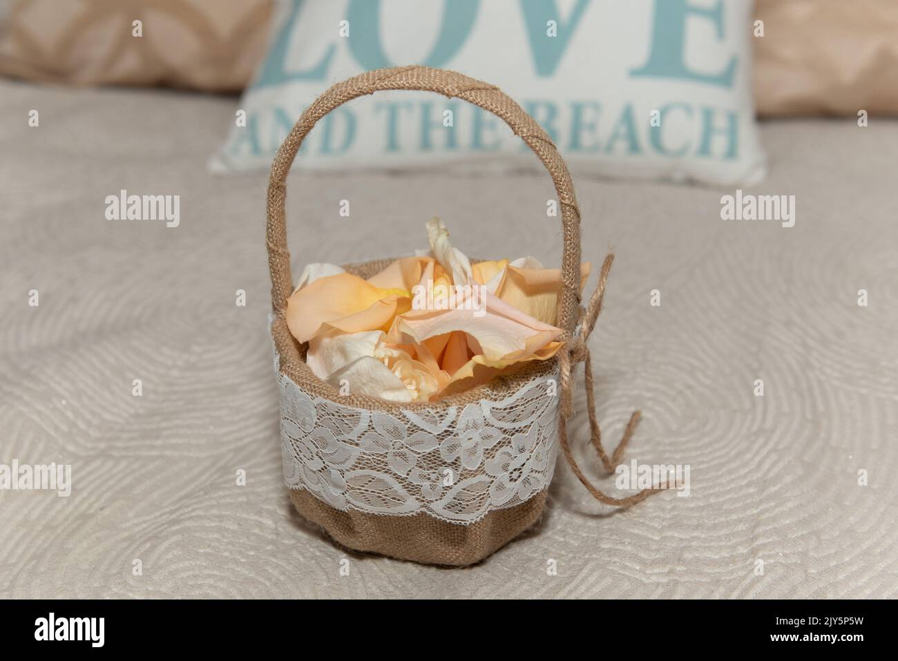Burlap basket is full of the flower petals to be spread in the wedding ceremony by the flower girl. Stock Photo