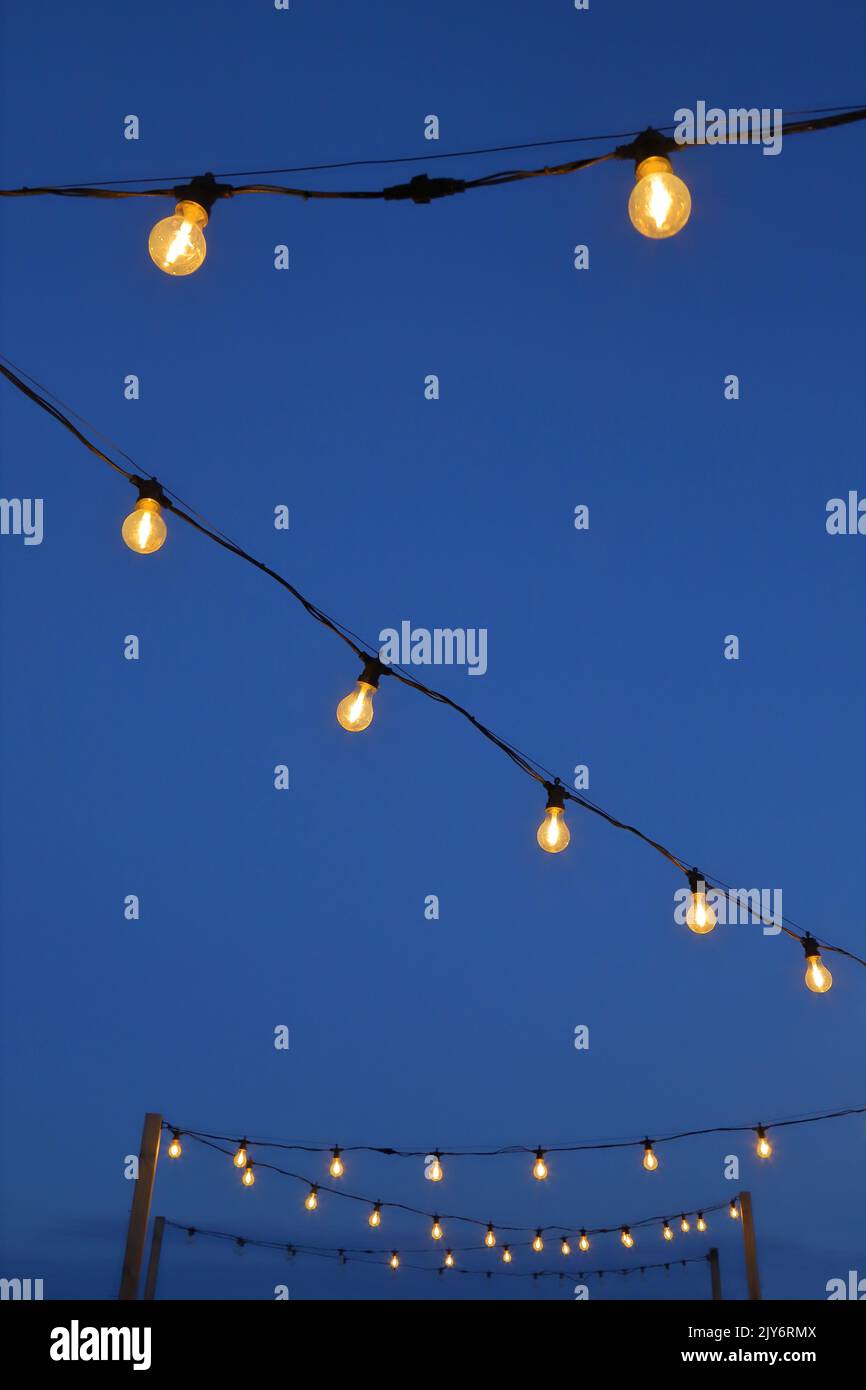Outdoor string light bulbs against blue sky Stock Photo
