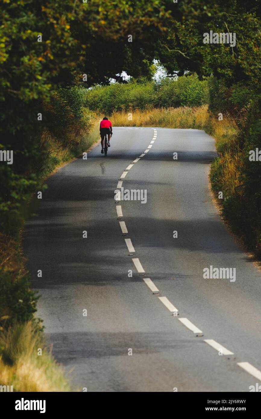 Alone bicyclist on the country road in Devon, UK Stock Photo