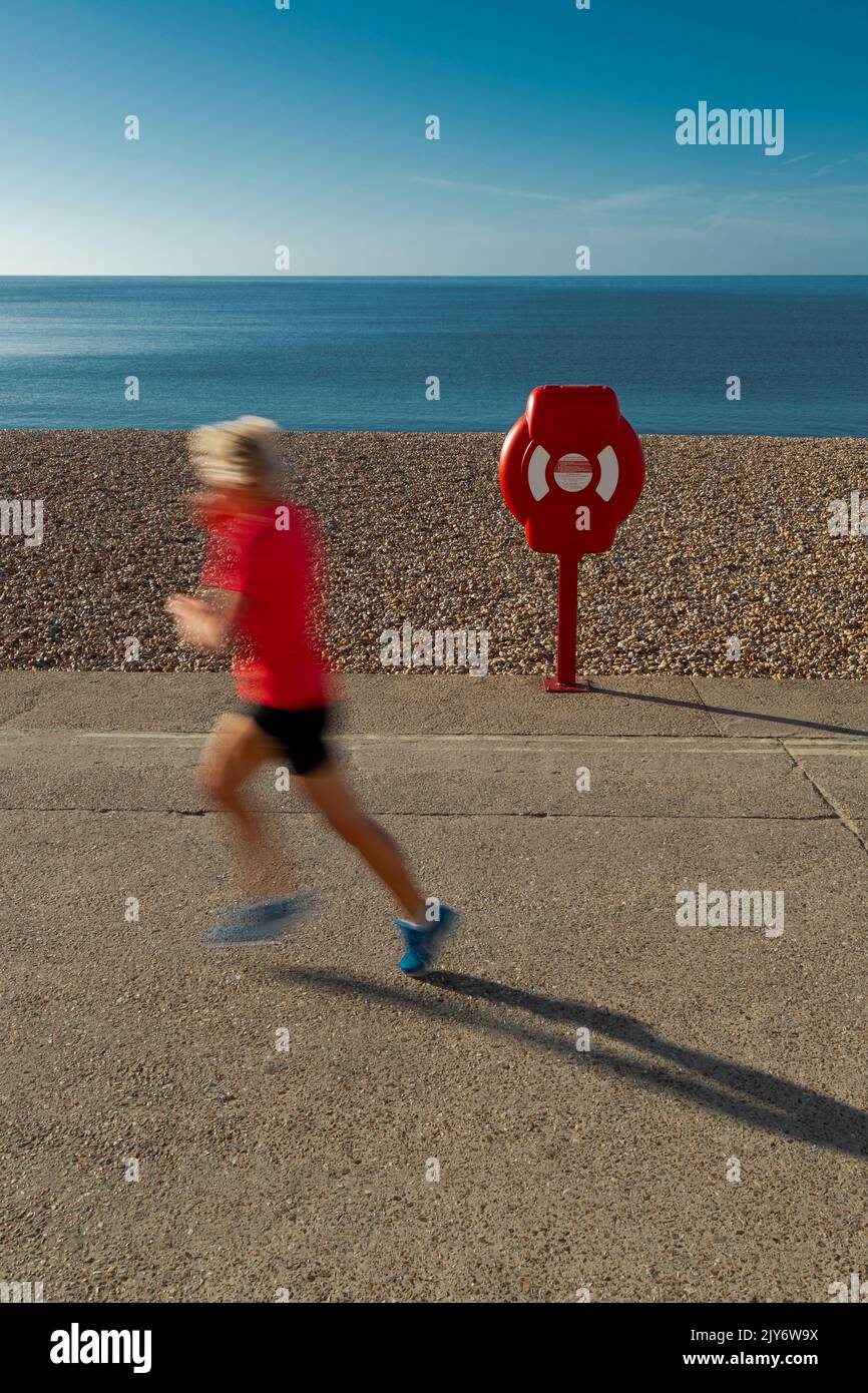 Blurred runner on a pebble beach of the Jurassic Coast in Lyme Regis, Dorset Stock Photo