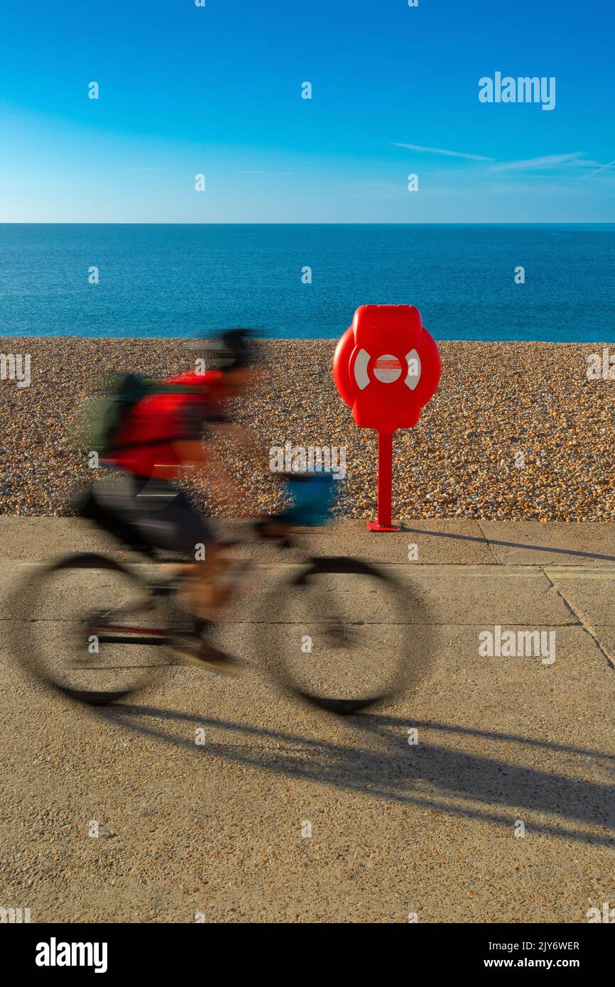 Blurred bicyclist on a pebble beach of the Jurassic Coast in Lyme Regis, Dorset Stock Photo
