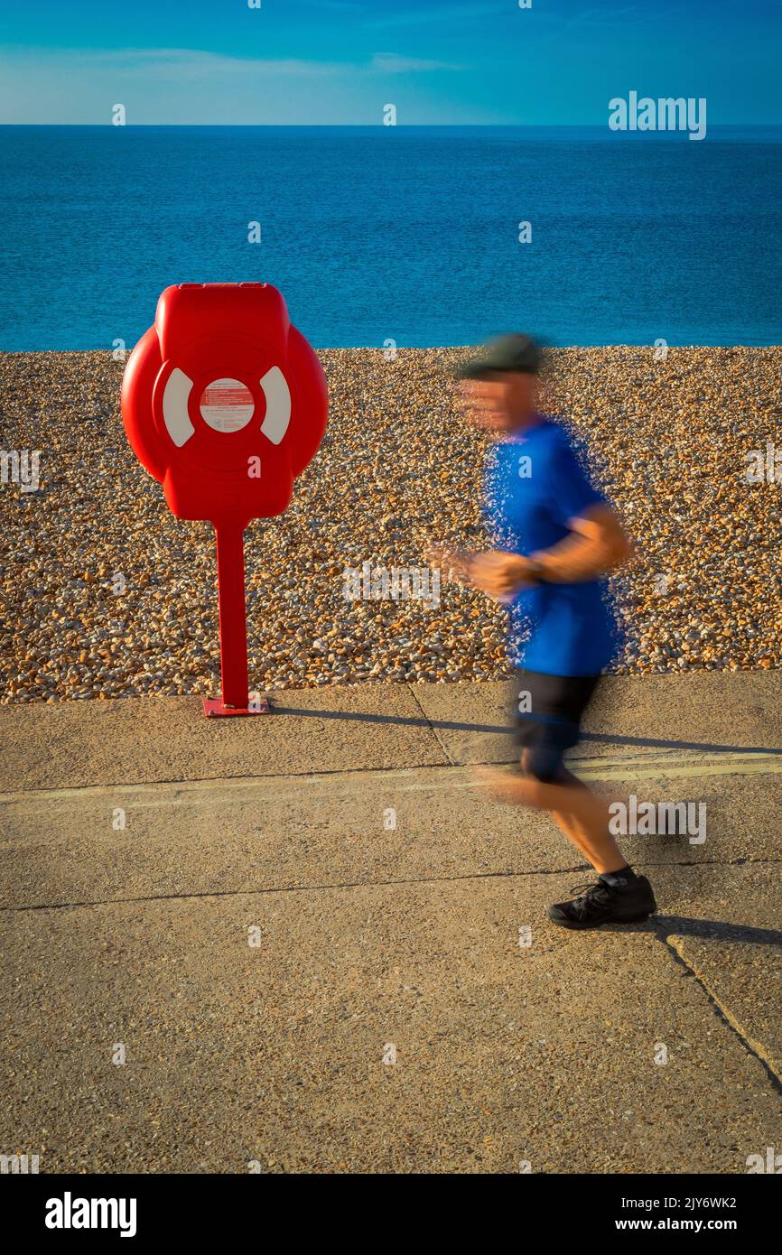 Blurred runner on a pebble beach of the Jurassic Coast in Lyme Regis, Dorset Stock Photo