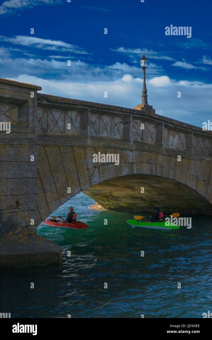 Kayakers under Axmouth Bridge on the river Axe near town of Seaton, Devon Stock Photo