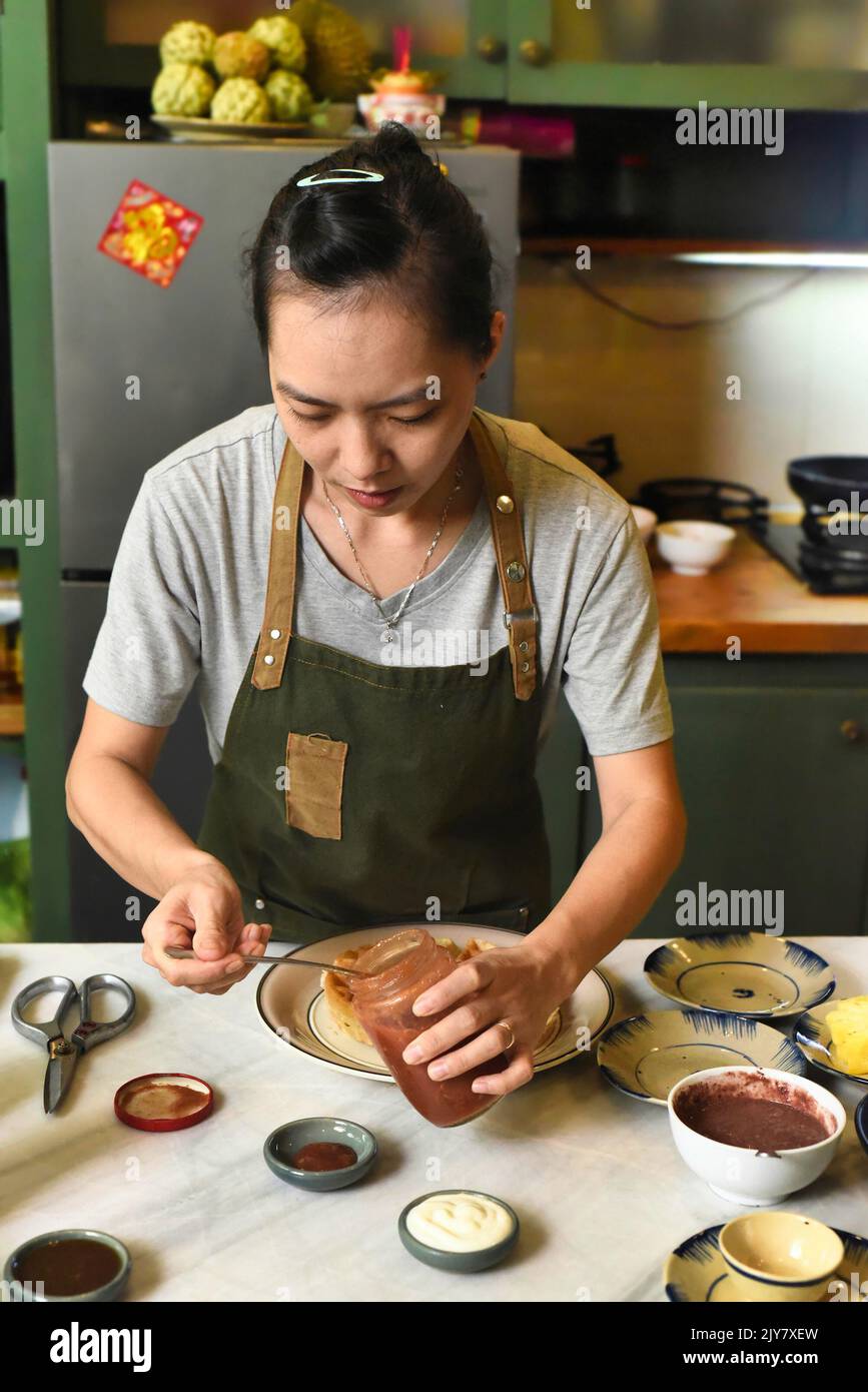 Vietnamese woman in apron serving foor on the table Stock Photo