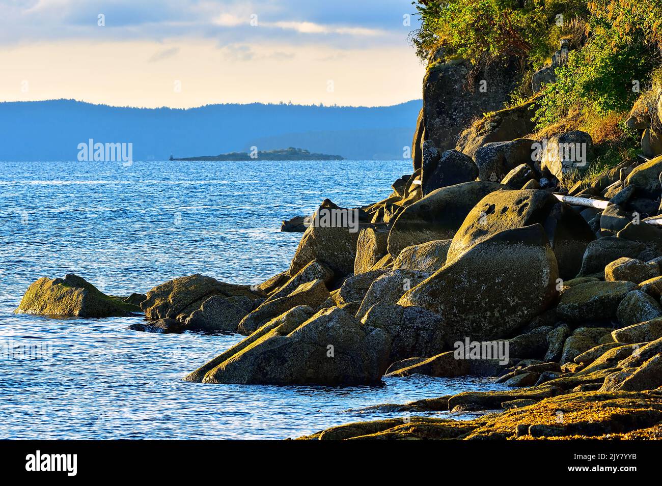 A landscape image of stones piled on the shore in the warm sunlight at Yellow Point on Vancouver Island British Columbia Canada. Stock Photo