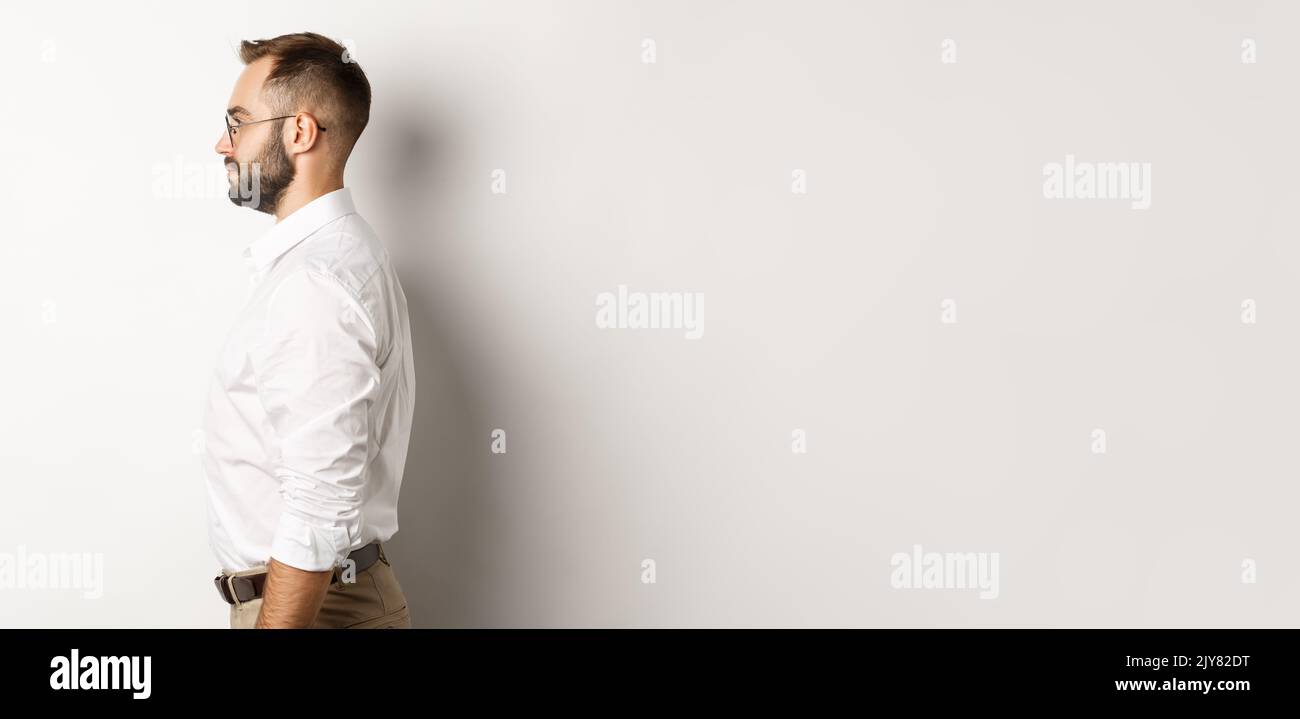 Left Standing Profile of young businessman in white collar shirt and beige pants ...