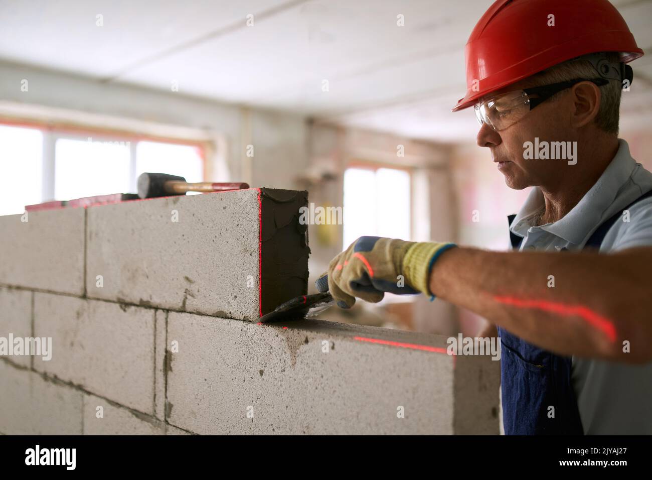 Bricklayer applies adhesive glue on autoclaved aerated concrete blocks