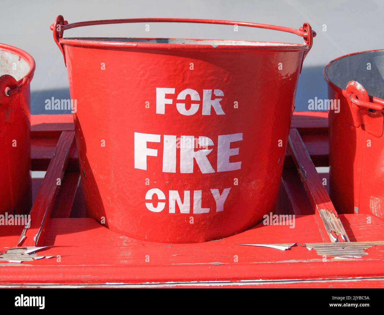 Bright red buckets labeled in white For Fire Only ready as protection