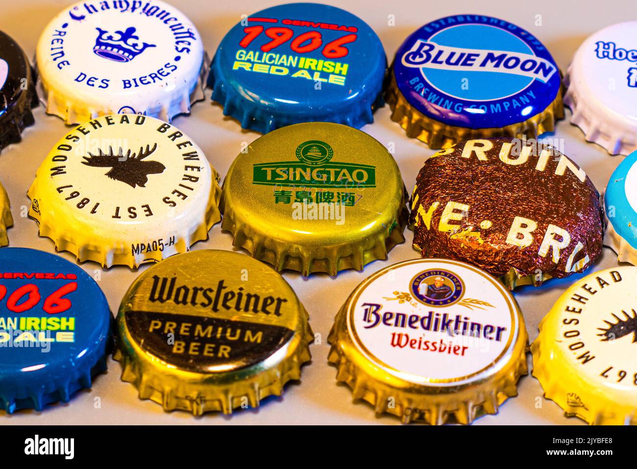 A variety of international beer bottle caps arranged in rows on a wood