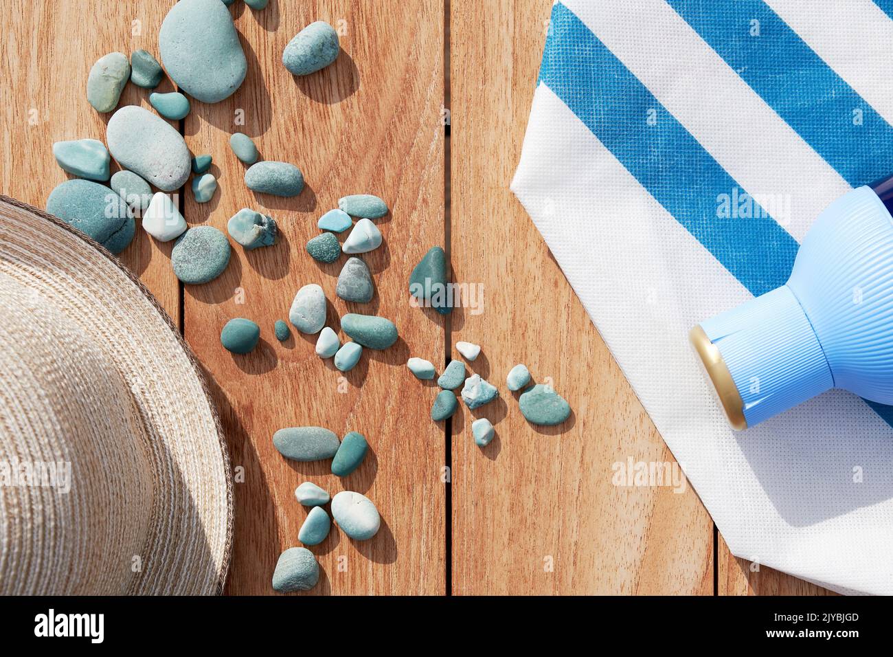 Beach accessories with vintage hat, cream bottle and sea pebbles on the wooden table. Summer beach accessories. Copy space for text Stock Photo