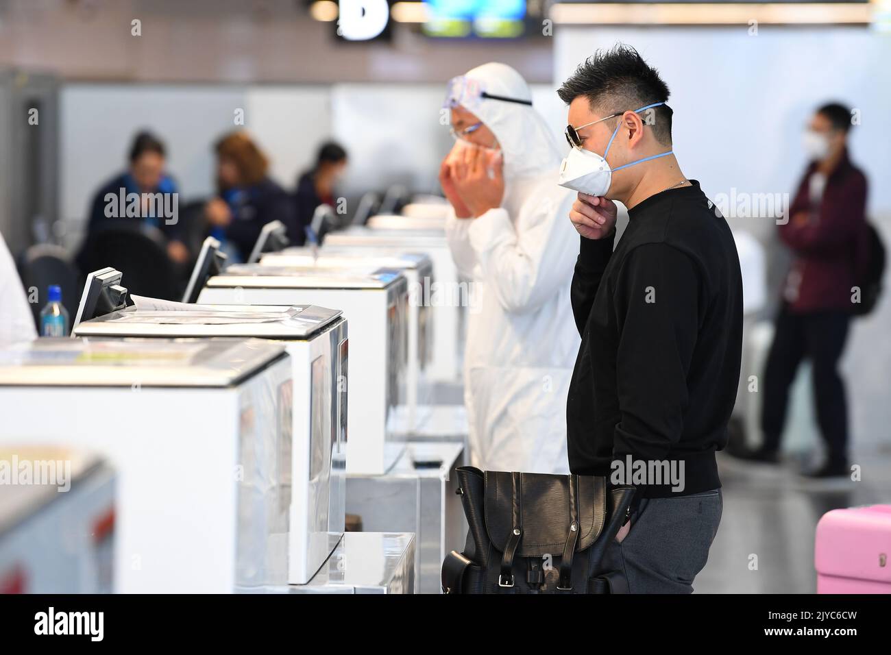 People in personal protective equipment are seen at the baggage checkin